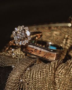 two wedding rings sitting next to each other on top of a gold cloth covered table