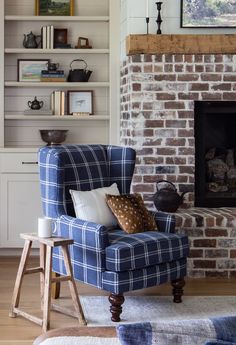 a blue chair sitting in front of a fire place next to a book shelf filled with books