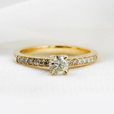 a yellow gold engagement ring with a single diamond in the center, on a white background