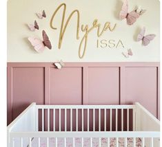 a baby's nursery room with pink walls and butterflies on the wall above the crib