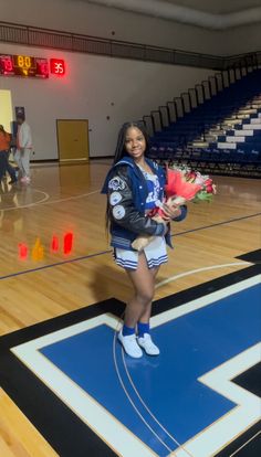 a woman standing on top of a basketball court holding flowers