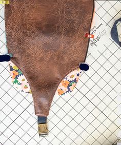 an overhead view of a brown leather bag on tiled flooring with other items around it