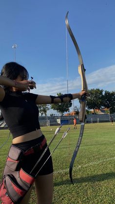 a woman is practicing archery on the grass