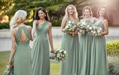 a group of women standing next to each other holding bouquets and wearing green dresses