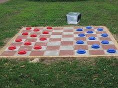 a giant checker board set up in the grass with blue and red cups on it