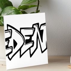 a black and white graffiti art piece on a table next to a potted plant