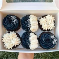 six cupcakes in a white box with blue frosting and sprinkles