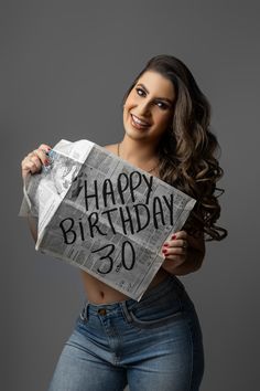 a woman holding up a newspaper with the words happy birthday 30 written on it