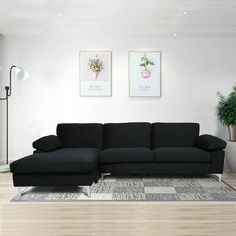 a living room with a black couch and two pictures on the wall