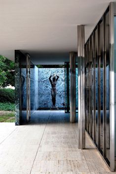 an empty hallway with glass doors and a person standing in the doorway on one side