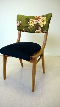 a wooden chair with floral fabric on the back and seat cushion, in front of a white wall