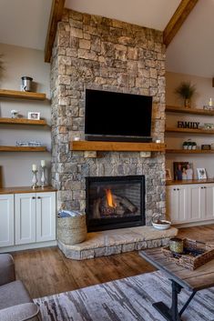 a living room with a stone fireplace and tv above the fire place in the center