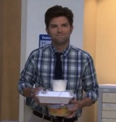 a man holding a box with a cup in it and a tie on his shirt