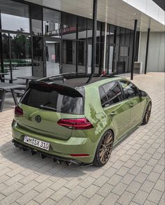 a green vw golf gtr parked in front of a building with large windows