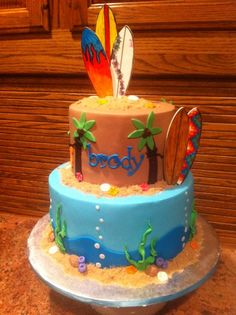 a three tiered cake decorated with surfboards and sand