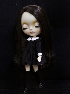 a doll with long black hair wearing a dress