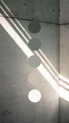 three circles hanging from the ceiling in an empty room with light coming through them and casting shadows on the wall