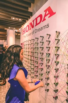 a woman is looking at a display with many wires on it and the words honda power of dreams