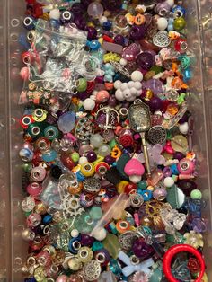 a plastic container filled with lots of different colored beads and charms on top of each other