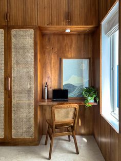 a chair and desk in a room with wood paneling on the walls, along with an open window