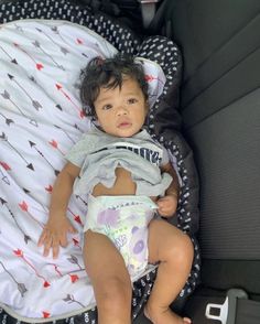 a small child laying on top of a bed in a car seat next to a blanket