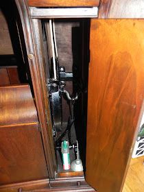 an old fashioned telephone in a wooden cabinet with other items on the floor and inside