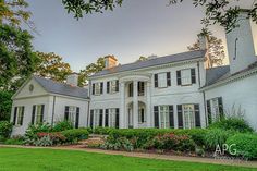 a large white house sitting on top of a lush green field