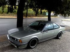 a silver car is parked on the side of the road next to some trees and bushes