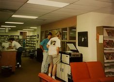 two men standing next to each other in a library