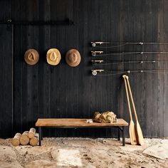 a wooden table sitting in front of a wall with hats hanging on it's sides