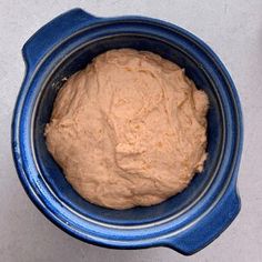 a blue bowl filled with dough on top of a table