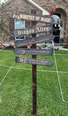 a wooden sign sitting on top of a lush green grass covered field in front of a brick building