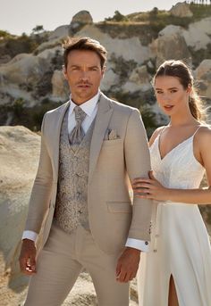 a man in a suit and tie standing next to a woman wearing a white dress