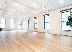 an empty room with wooden floors and large windows