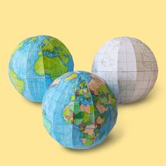 three different colored globes sitting on top of each other in front of a yellow background