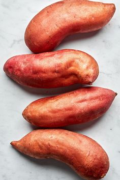 three sweet potatoes sitting next to each other on a white counter top, one is red and the other is yellow