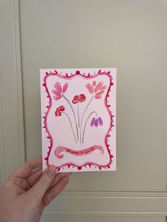 a hand holding up a card with flowers on it