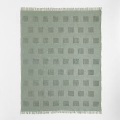 a green rug with squares and fringes on it