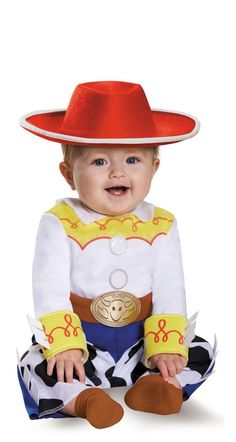 a baby in a toy story costume sitting on the ground wearing a red cowboy hat