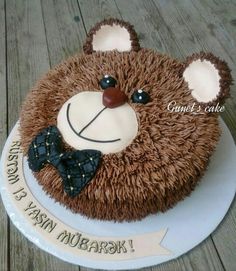 a birthday cake with a teddy bear design on the front and sides, sitting on top of a wooden table