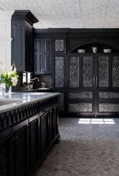 a large kitchen with black cabinets and marble counter tops, along with an island in the middle