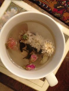 a cup filled with water and flowers on top of a table