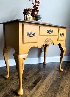 a yellow table with two drawers on top and some vases on the shelf next to it