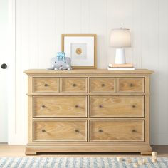 a wooden dresser sitting next to a white door with a blue teddy bear on top