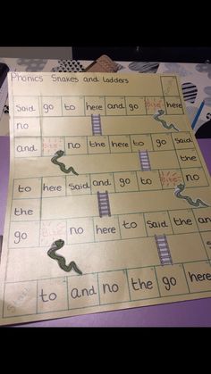 a close up of a game on a table with paper cut out to look like snakes and ladders