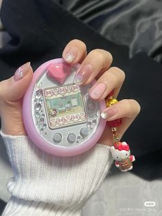 a person holding a hello kitty toy in their hand with pink and white designs on it