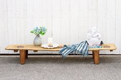 a wooden bench with two vases on top of it next to a book and candle