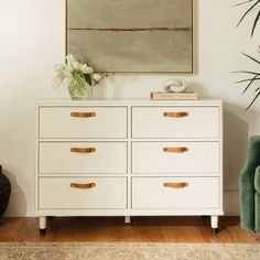 a white dresser with gold handles in a living room