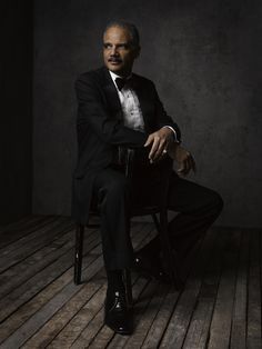 a man in a tuxedo sitting on a chair