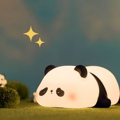 a panda bear laying on top of a lush green field next to a yellow star